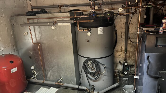 Vatten- och värmetankar med rörsystem i källare, kopplade enligt installation.