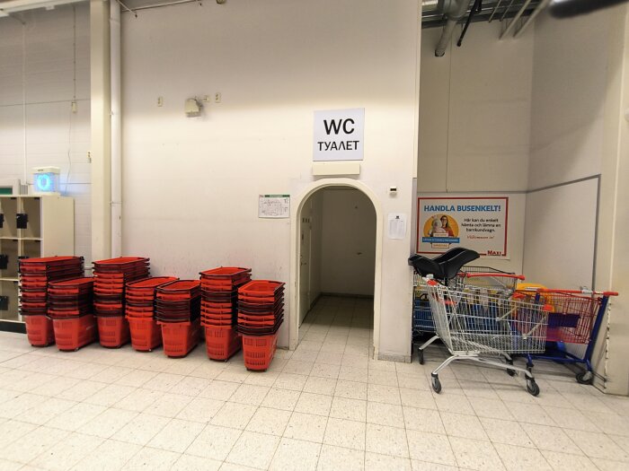Ica Maxi interiör med kundkorgar, kundvagnar och WC-skylt på svenska och ryska.