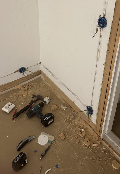 Elektrisk installation med frästa kablar i tretexvägg, omgivna av verktyg och byggrör, senare avsett att täckas med gipsskivor.