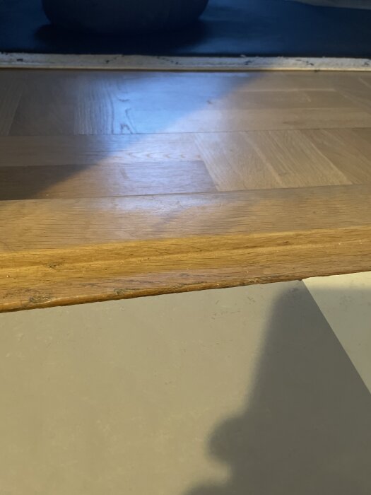 Golv i kök med övergång mellan Forbo Marmoleum och träparkett, synlig skarv vid ingång, färgerna moon och orbit, 5mm kant kvarstår.