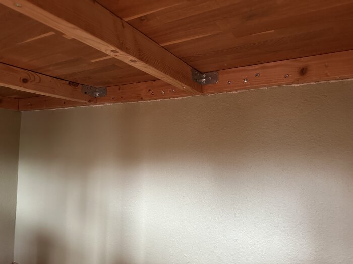 Kattopalkki kiinni seinässä metallikannattimien avulla. Rakennusprojekti, jossa oli vaikeuksia asentaa pluggeja.