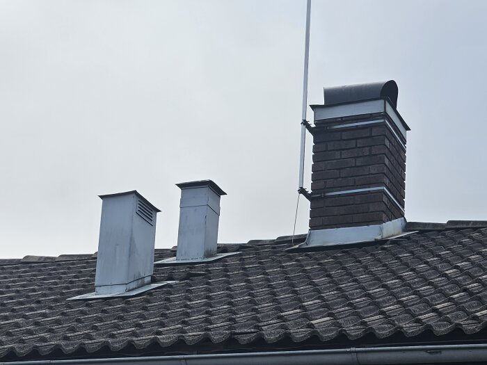 Ventilationsutgångar och skorsten på ett tegeltak, med anordningar för frånluftsventilation.