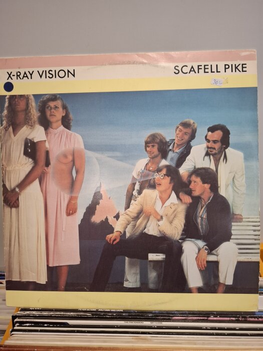 Skivomslag för "X-Ray Vision" av Scafell Pike, visar en grupp människor klädda i 1980-talsmode med berg i bakgrunden.