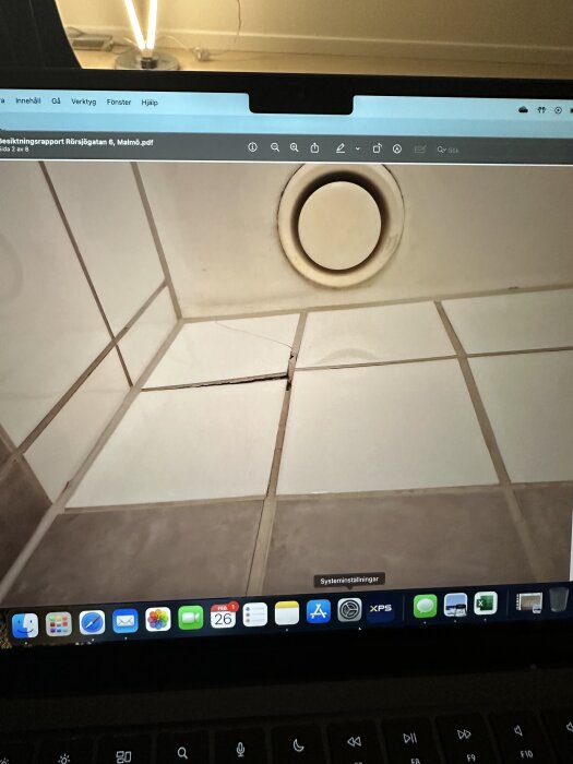 Spricka i kakelväggens fog på ett badrumstak med synlig ventilation, fotograferat på en datorskärm.