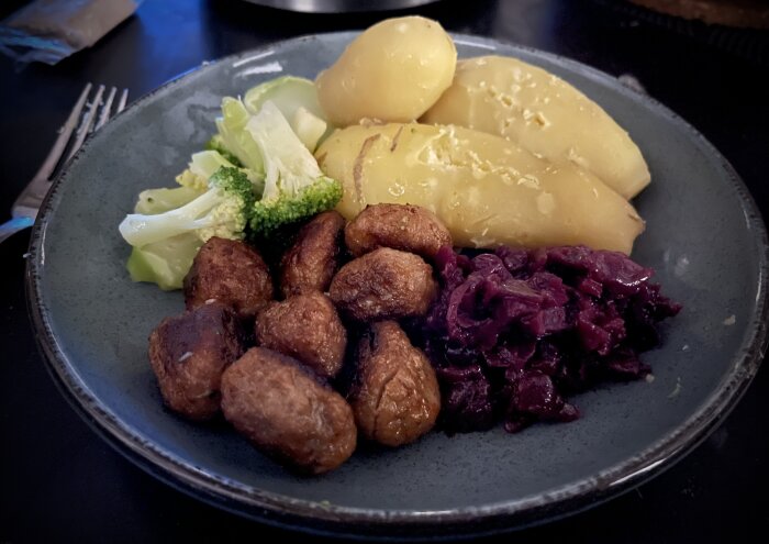 Tallrik med köttbullar, mandelpotatis, rödkål och kokt broccoli.