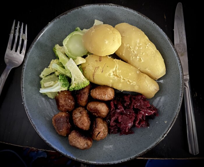 Tallrik med köttbullar, mandelpotatis, rödkål och kokt broccoli.