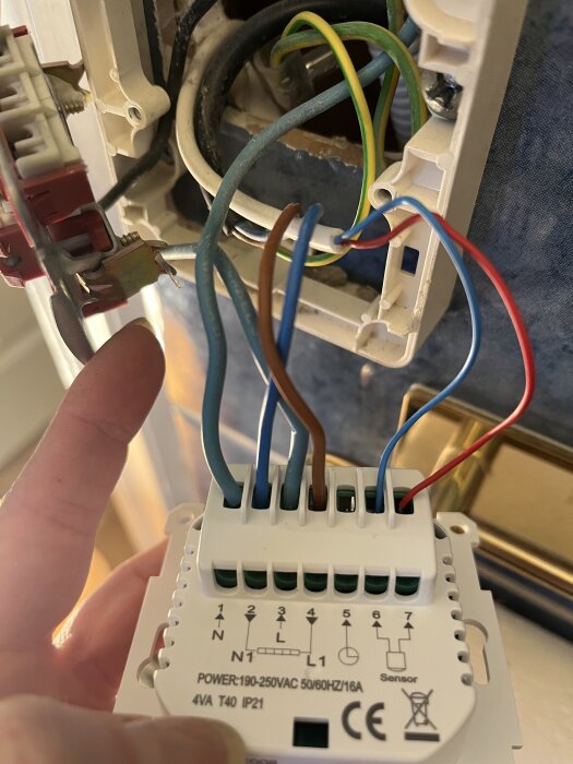 Kopplingsbild av ny termostat för golvvärme med synliga ledningar i anslutningsblock.