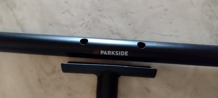 Handtag till jordborr med texten "PARKSIDE" synligt på det svarta röret, visar hål för montering eller justering.