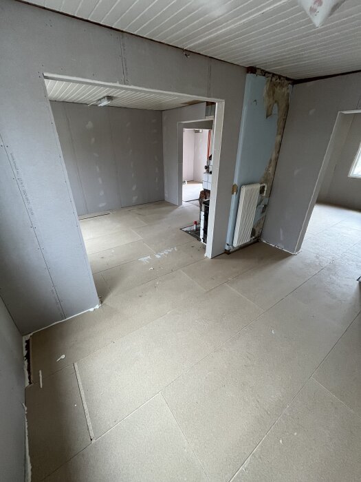 Rum med lagd golvspån innan spackling, synliga väggar och tak.