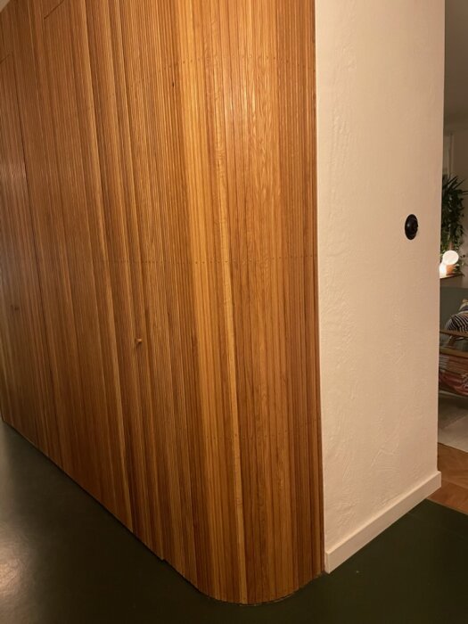 Träpanelvägg med ribbor och rundade hörn, stabil konstruktion med dolda gångjärn, ljus träfinish, del av ett hemmabygge.