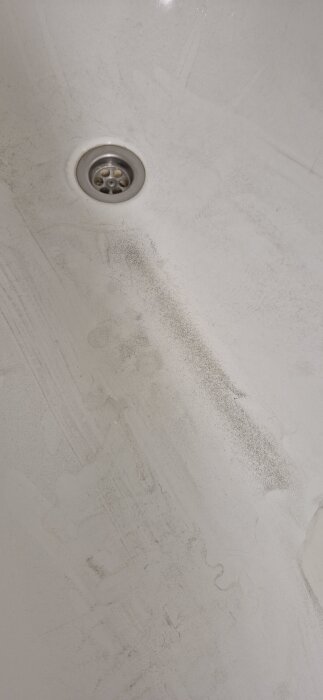 Mörkt sediment i ett vitt badkar efter urtappning från nyborrad brunn.