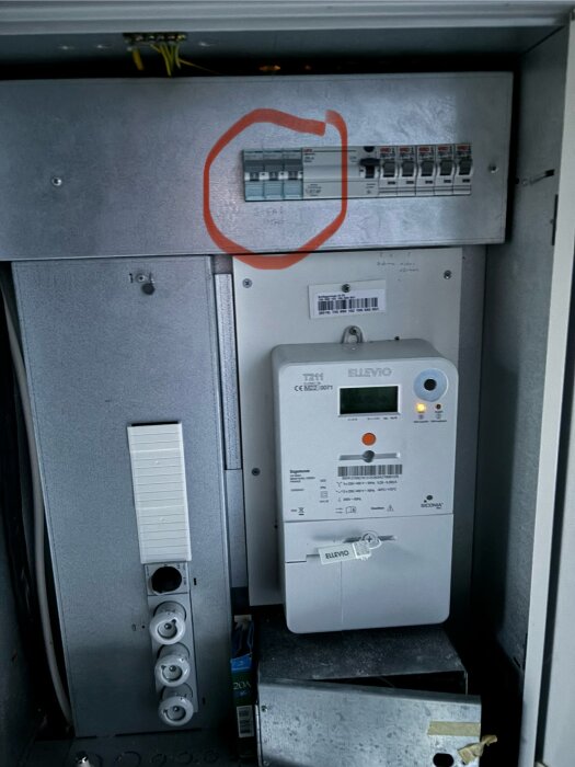 Elskåp med elmätare, säkringar och uttag. En säkring är inringad med röd penna för att visa uppsäkringen för ett 3-fasuttag.
