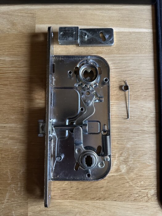 Demonterad Assa Abloy 4565 låskista med fjäder placerad bredvid; användare söker hjälp med montering.