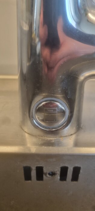 Trådlös knapp på diskbänk, designad för att styra vattenflödet till diskmaskin. Knappen är batteridriven och har en symbol på ytan.