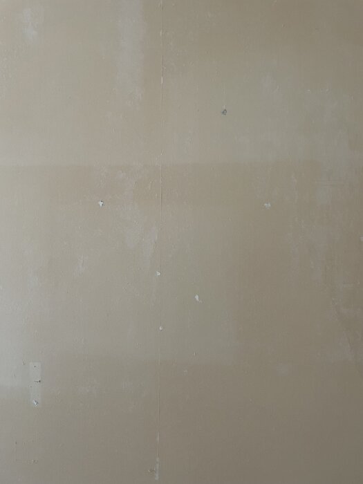 Nedriven tapet visar ojämn yta av gipsvägg med rester och nivåskillnader efter användning av ångmaskin under renovering.