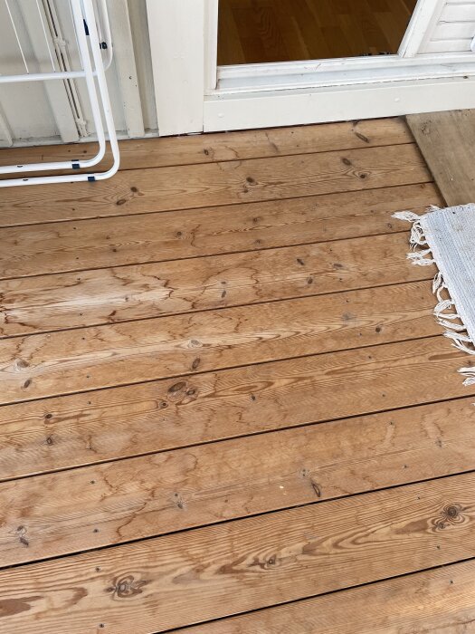 Trägolv av kärnfuru med mörka fläckar på inglasad men oisolerad altan.