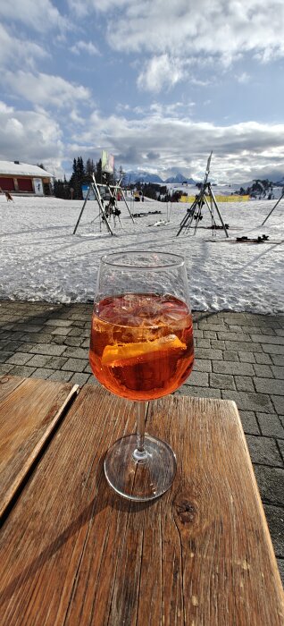 Aperol Spritz på ett träbord med skidbacke i bakgrunden.