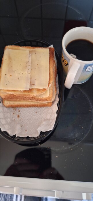 Rostade brödskivor med ost staplade på en tallrik bredvid en kopp svart kaffe.