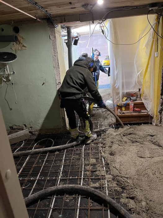 Personer som arbetar med att gjuta ett golv i en renoveringssituation.