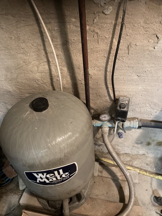 Trycktank hydrofor i källare med anslutna rör och tryckmätare, används för att diskutera vattenavstängning och avledning vid avhärdningsfilter.
