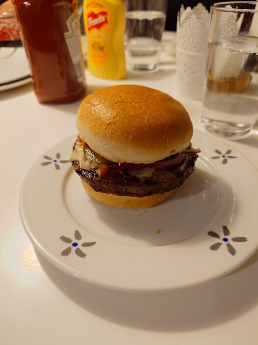 Hamburgare med picklad lök och Väddö Cheddar tryffel på en vit tallrik; ketchup och senap syns i bakgrunden.