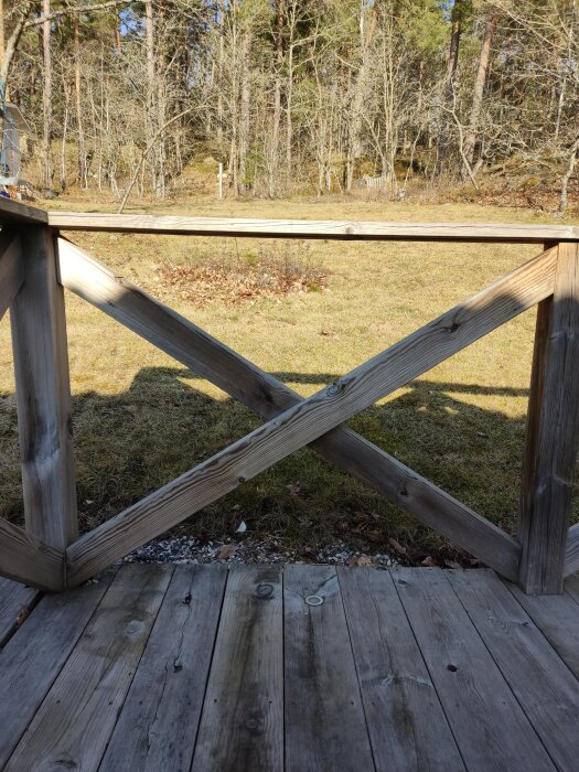 Träaltan med räcke i en sluttande trädgård omgiven av skog, diskussion om terrassering av marken.