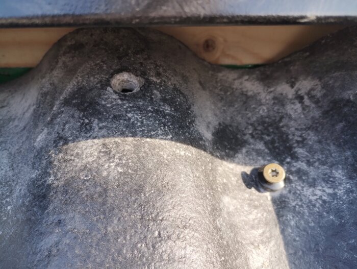 Hål och skruv i en takpanna under takkupan, visar på möjliga problem med takrenoveringen.