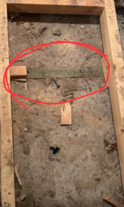 Träram ovanpå betonggolv med grönt reglar och möjligt mögel; markerad med röd cirkel.