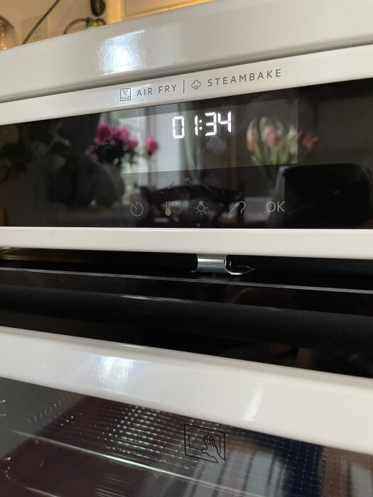 Närbild på Electrolux spis ugnslucka och display som visar "01:34", utan synlig spärr för ugnsluckan.