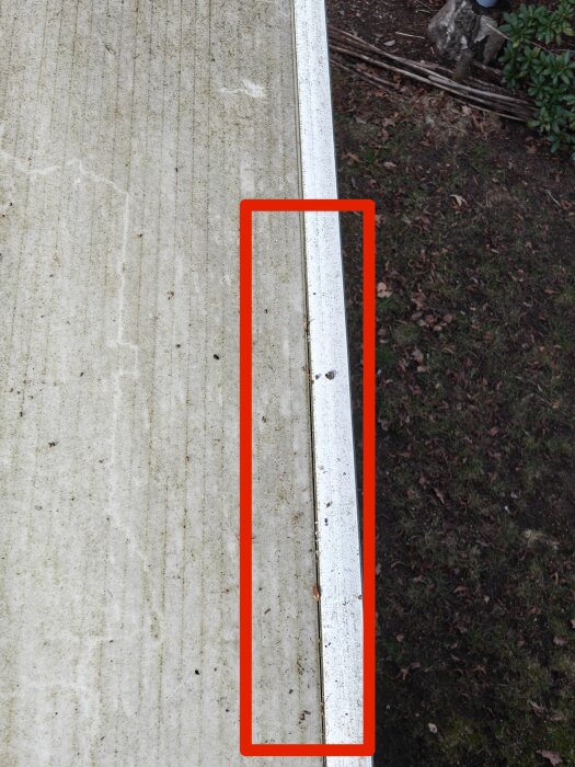 Takskiva med spricka, visas från sidan. En röd markeringsram kring en del där taket sticker ut och listen är synlig.