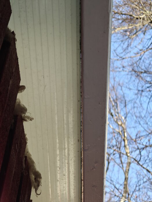 Takutsprång med plasttak och träpanel, blå himmel i bakgrunden.