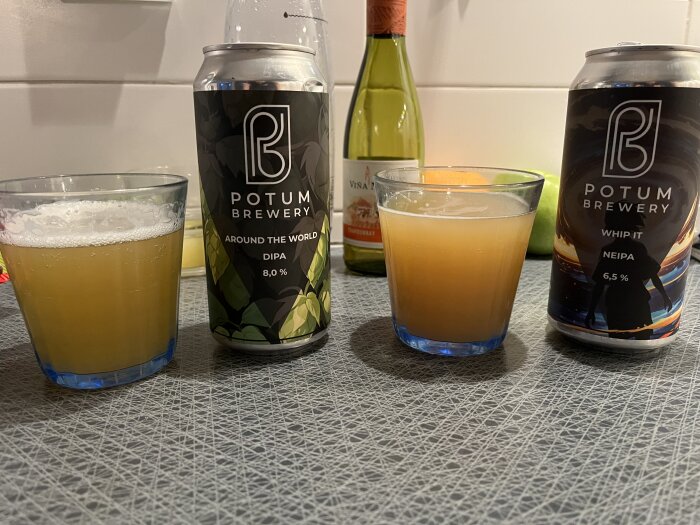 Två glas med öl bredvid burkar från Potum Brewery: "Around the World DIPA" och "Whip It NEIPA", på en köksbänk.