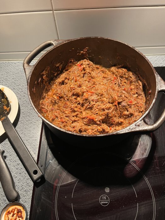 Gryta med långkokt chili i en stor kastrull på en spishäll.