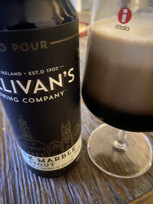 Flaska och glas med Sullivans Brewing Company Black Marble Stout på ett bord.