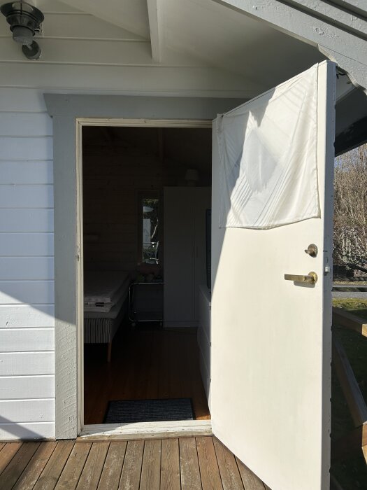 Friggebodsdörr från 90-talet står öppen med trasig dörrbeklädnad.