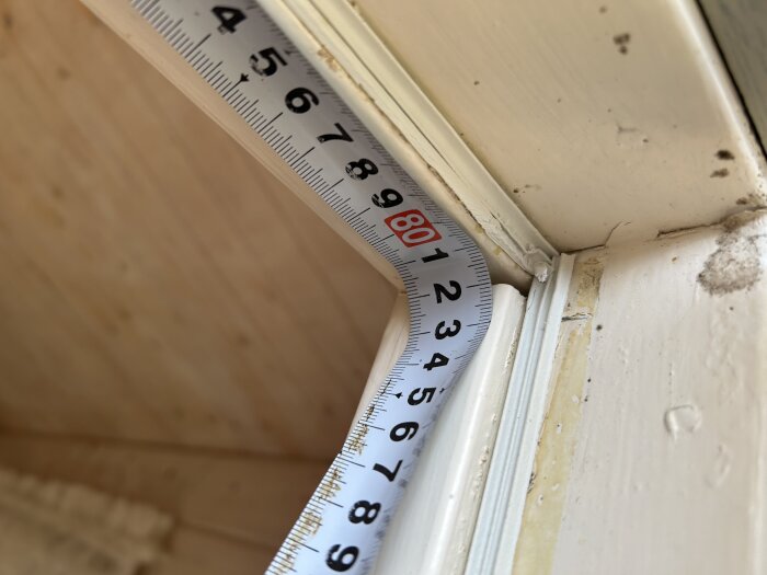Måttband mäter innermåttet på dörrkarmen i en friggebod, visar cirka 80 cm.