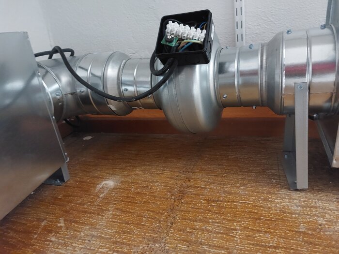 Värmeflyttare med ljuddämpare installerad i kattvind, visas med metallkanaler och kablage som transporterar kall luft.