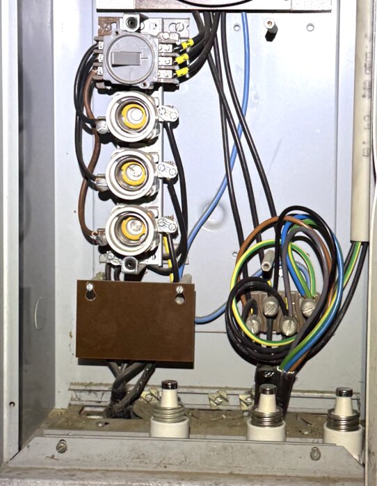 Överfulla terminaler för L1, L2, L3 och PEN i mätarskåp med flera kablar; begränsat utrymme och saknade DIN-skenor för anslutningar.