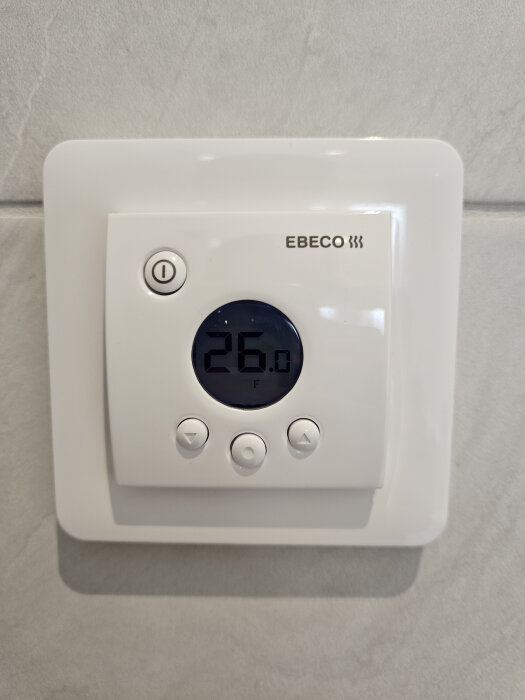 En Ebeco 205 termostat visar 26 grader på en ljus vägg.