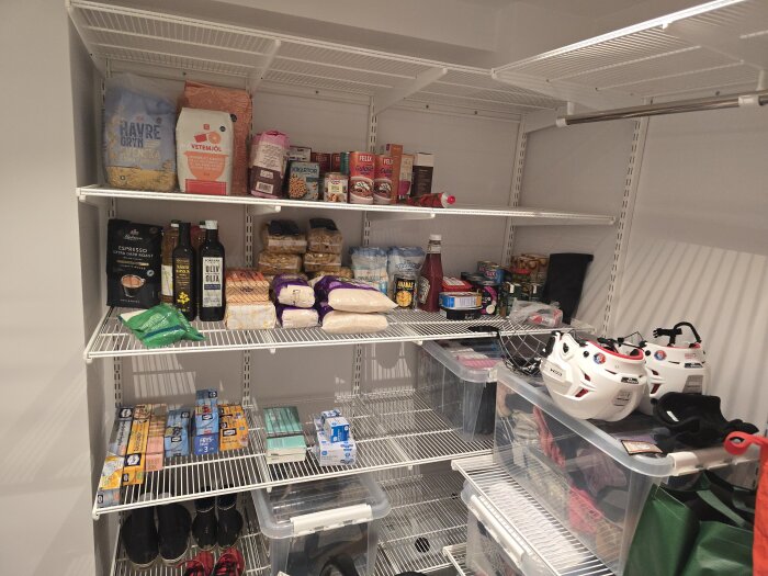 Organiserade hyllor i tvättstugan med matvaror som pasta, olja och konserver samt förvaringsboxar och hjälmar.