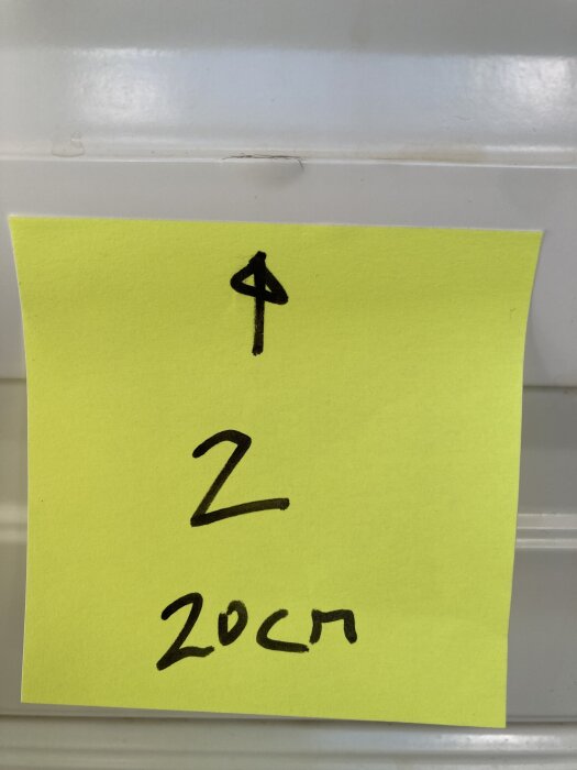 Gul post-it-lapp på kökslucka visar pil uppåt, siffran 2 och texten "20 cm", kanske markerar lackskada enligt diskussionen om Ikea Metodkök.