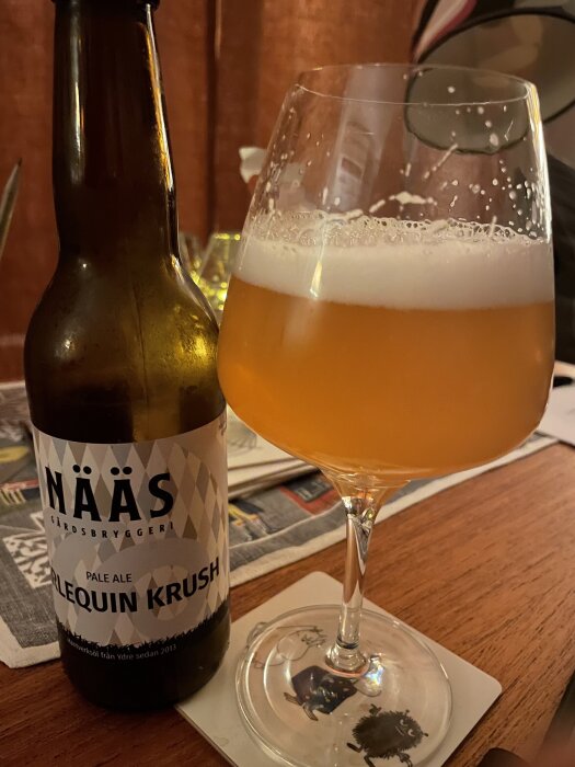 Flaska och glas med svensk pale ale från Näås gårdsbryggeri på träbord.