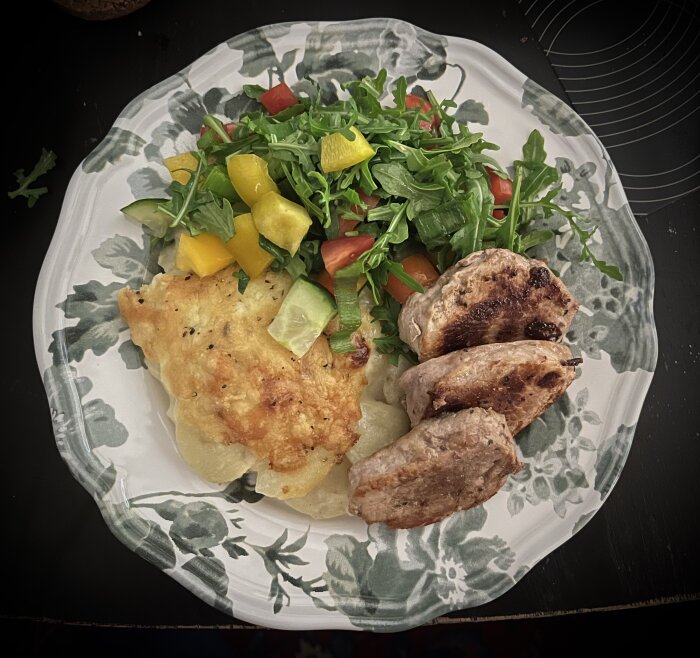 Stekt fläskfilé med potatisgratäng och sallad på en blommig tallrik.
