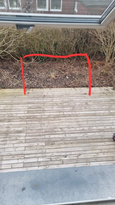 Trädäck med gränsområde markerat i rött för utbyggnad, omgiven av buskar.