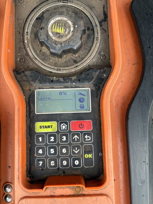 Display och knappsats på en Worx WG790e robotgräsklippare. Skärmen visar "Laddar 0%" och knapparna inkluderar "Start" och "OK".