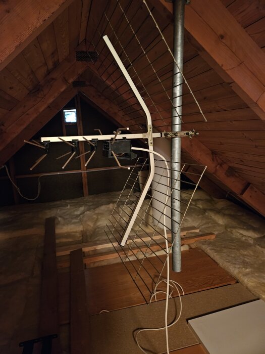 Yagi UHF-antenn monterad i vinden, cirka 60 cm hög, fäst vid ett metallrör med träpaneler i bakgrunden.