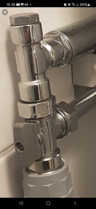 Kromad vattenventil med T-koppling och kopparrörsanslutning i badrum.