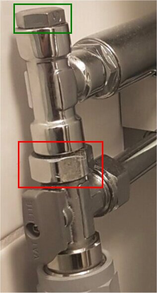 Blank T-koppling med grönt markerad stopp-plugg och röd övergång till kulventil, sitter ihop med metalliska rör.