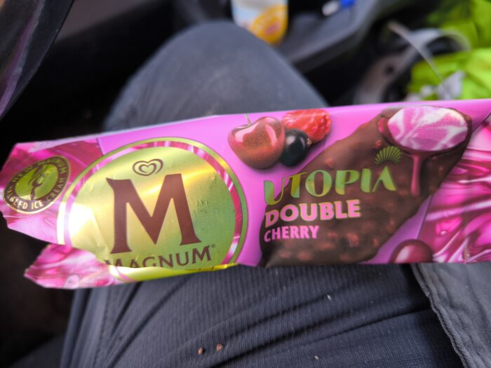 Förpackning av Magnum Utopia Double Cherry glass mot bakgrund av en bilstol.