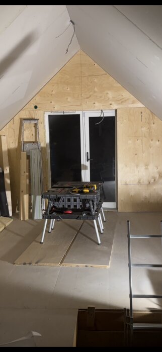 Arbetsbord med flera Dewalt-verktyg i ett under renovering med stege och byggmaterial runtom.
